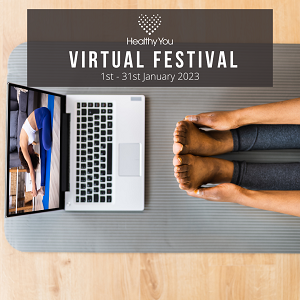 Person sitting on the floor participating in a fitness class by watching along on a laptop