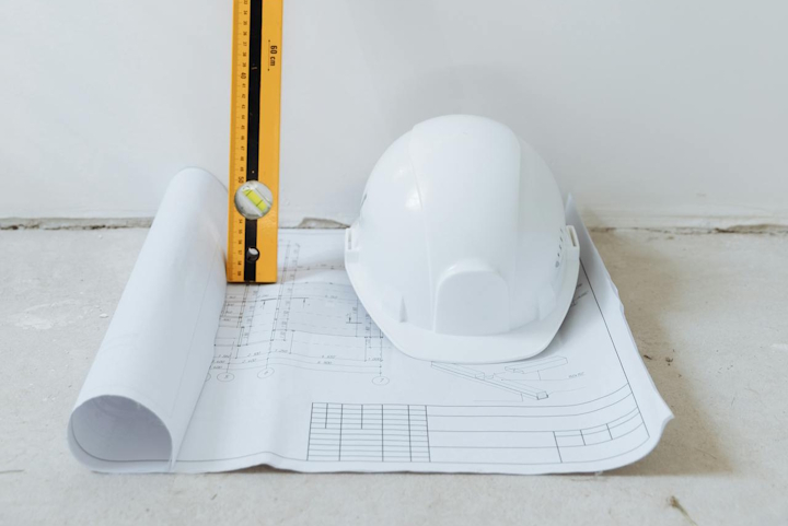 Building plans with a hard hat and spirit level