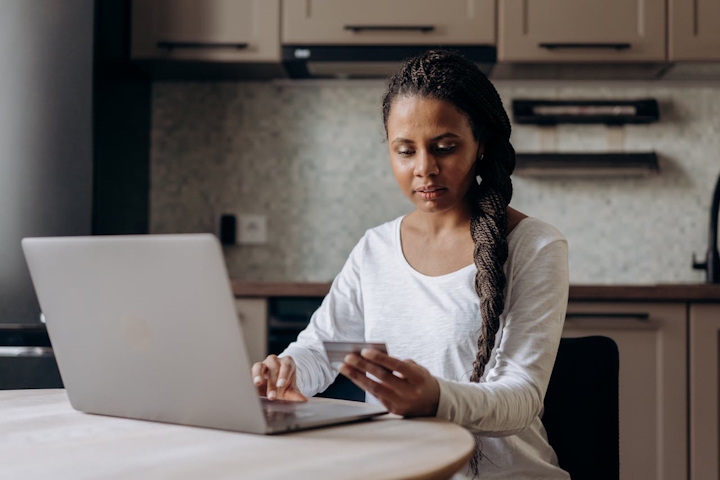 Woman using a laptop and holding a bank card