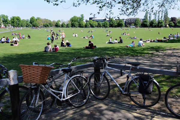 Bike storage and people enjoying the sun near the south corner of Parker's Piece